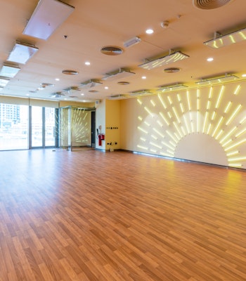 Fitness First, Marina Gate Empty fitness studio featuring wooden floors, large windows with city views, and a wall with sunburst LED lighting.