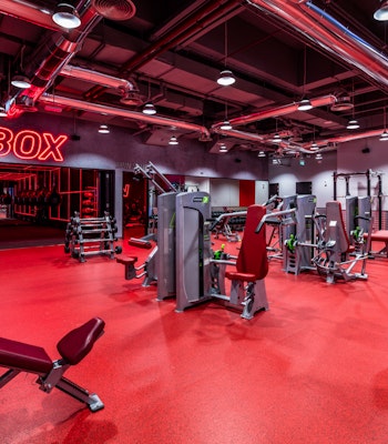 Fitness First, The Palm Dubai A red-themed gym with various workout machines and equipment, including a "BOX" sign on the wall.