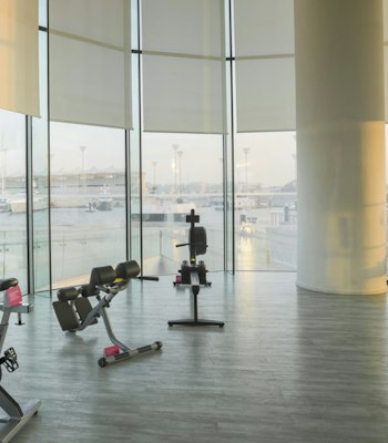FIT Gym, W Abu Dhabi Gym area with stationary bikes, benches, and floor-to-ceiling windows providing ample natural light and cityscape views.