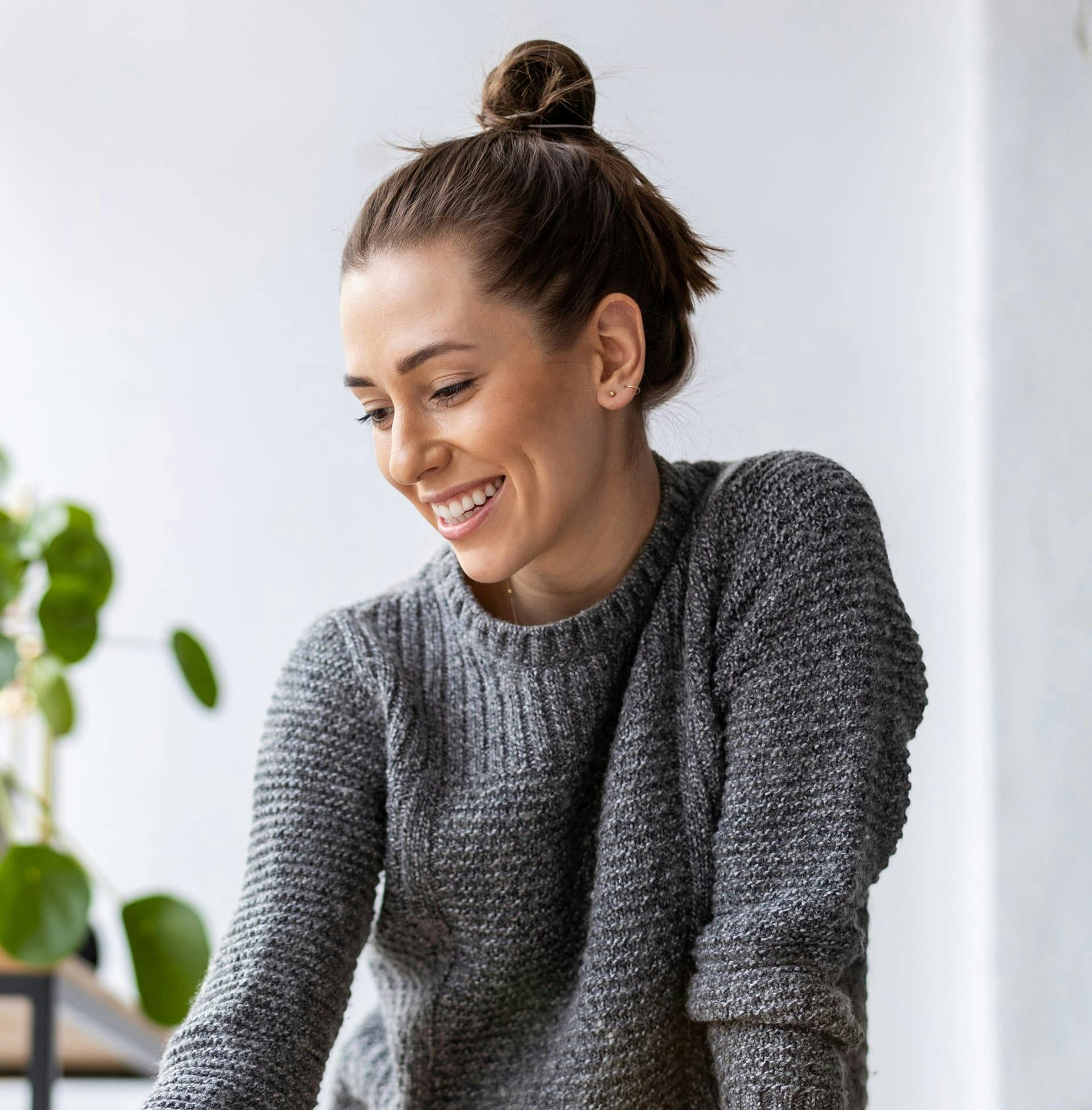 woman in grey sweater with her hair in a bun