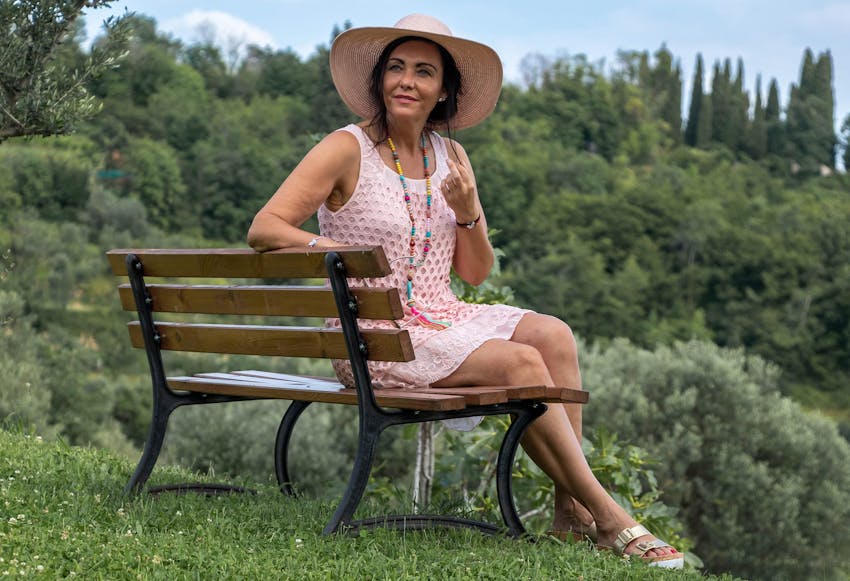 woman in dress and hat sitting on bench