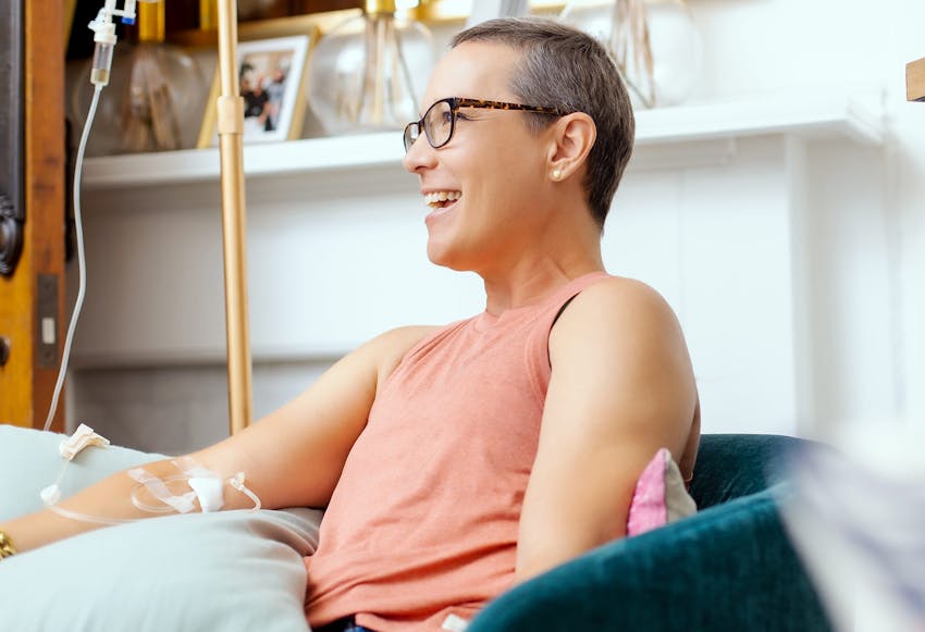 woman smiling and sitting down doing iv therapy