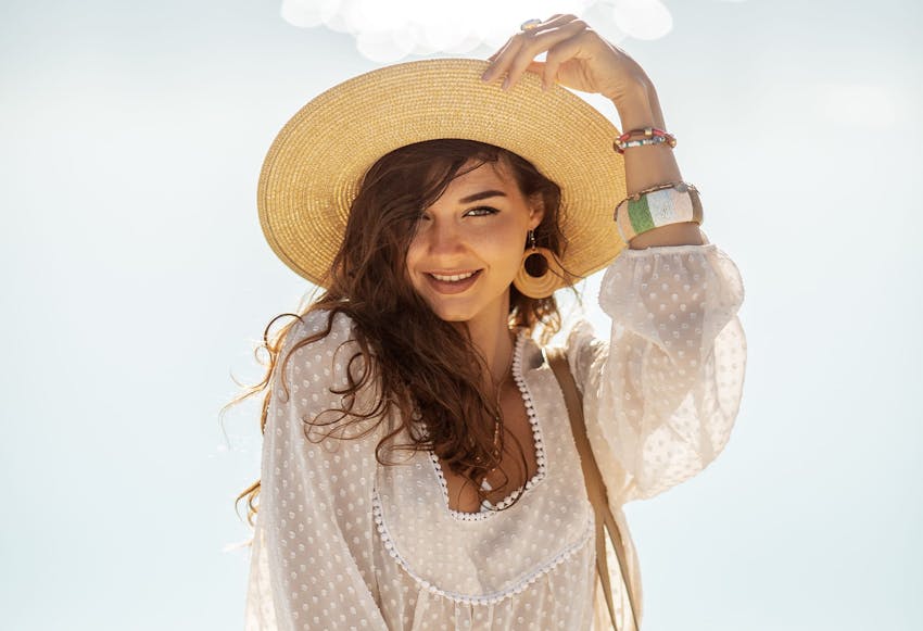 woman holding edge of hat