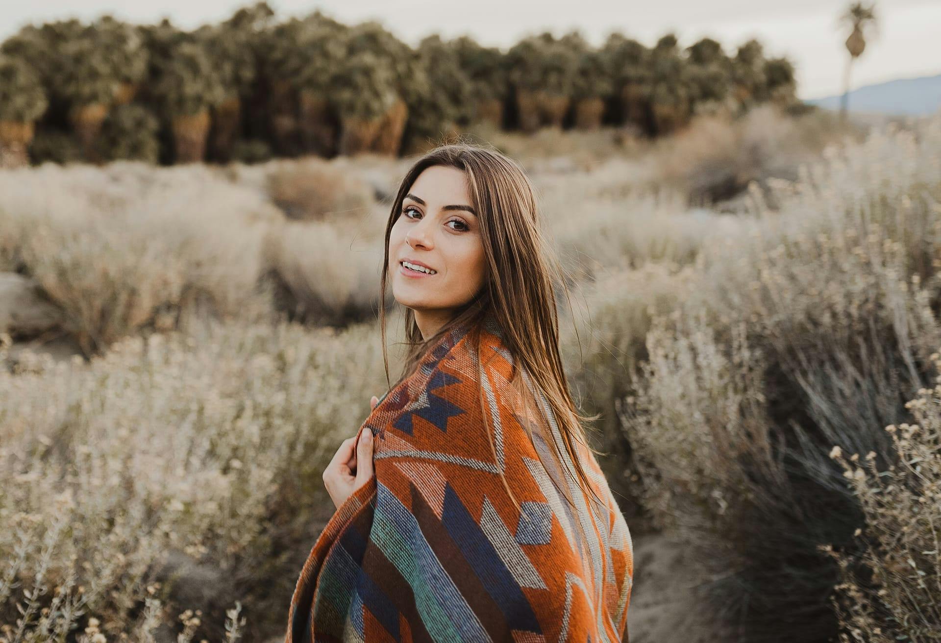 woman with dry bushes around wearing colorful top