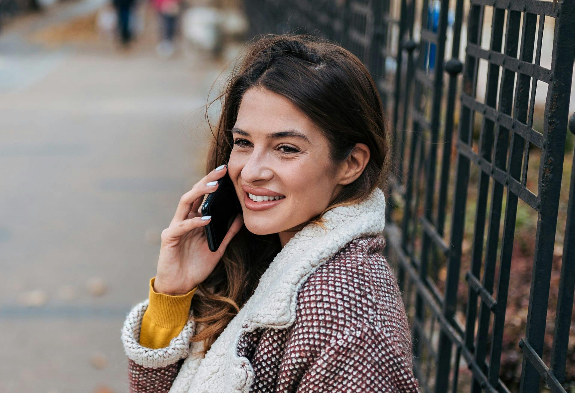 woman putting phone to her ear while on sidewalk
