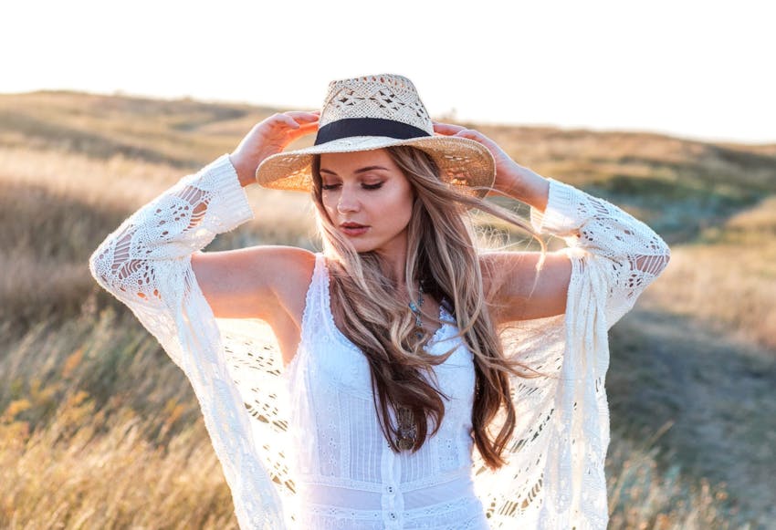 woman holding her sunhat with white coverup on