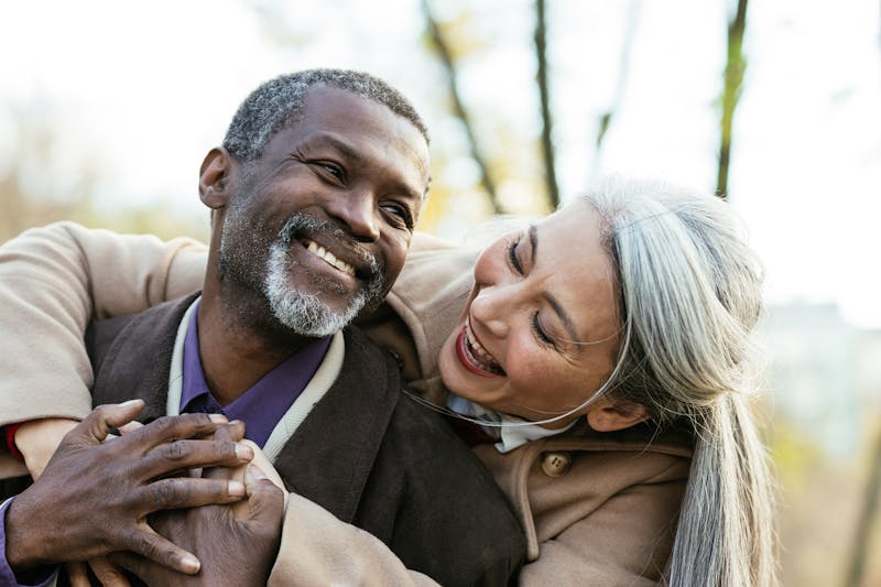 woman hugging man from behind and both are smiling