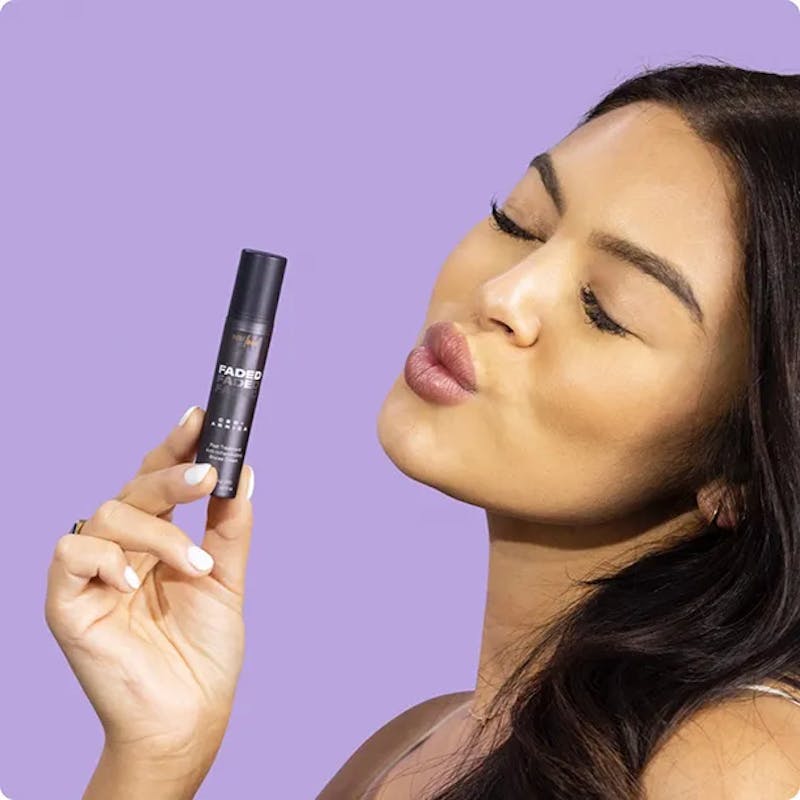 woman puckering her lips while holding a makeup product