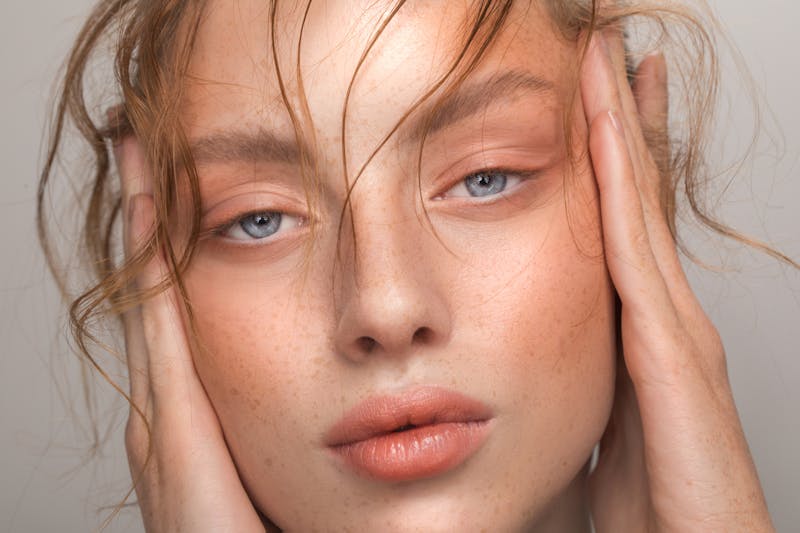 woman with blue eyes touching the sides of her face