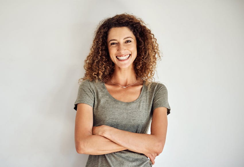 woman in gray shirt smiling with arms crossed