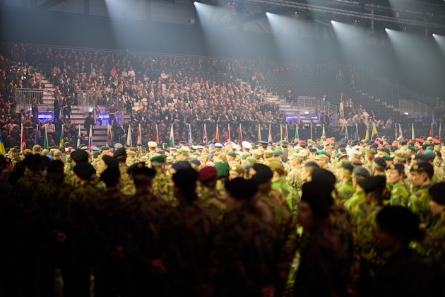 Cerimonia di apertura dei 5° Giochi mondiali militari invernali a Lucerna, con i soldati schierati e le bandiere nazionali davanti a una tribuna gremita