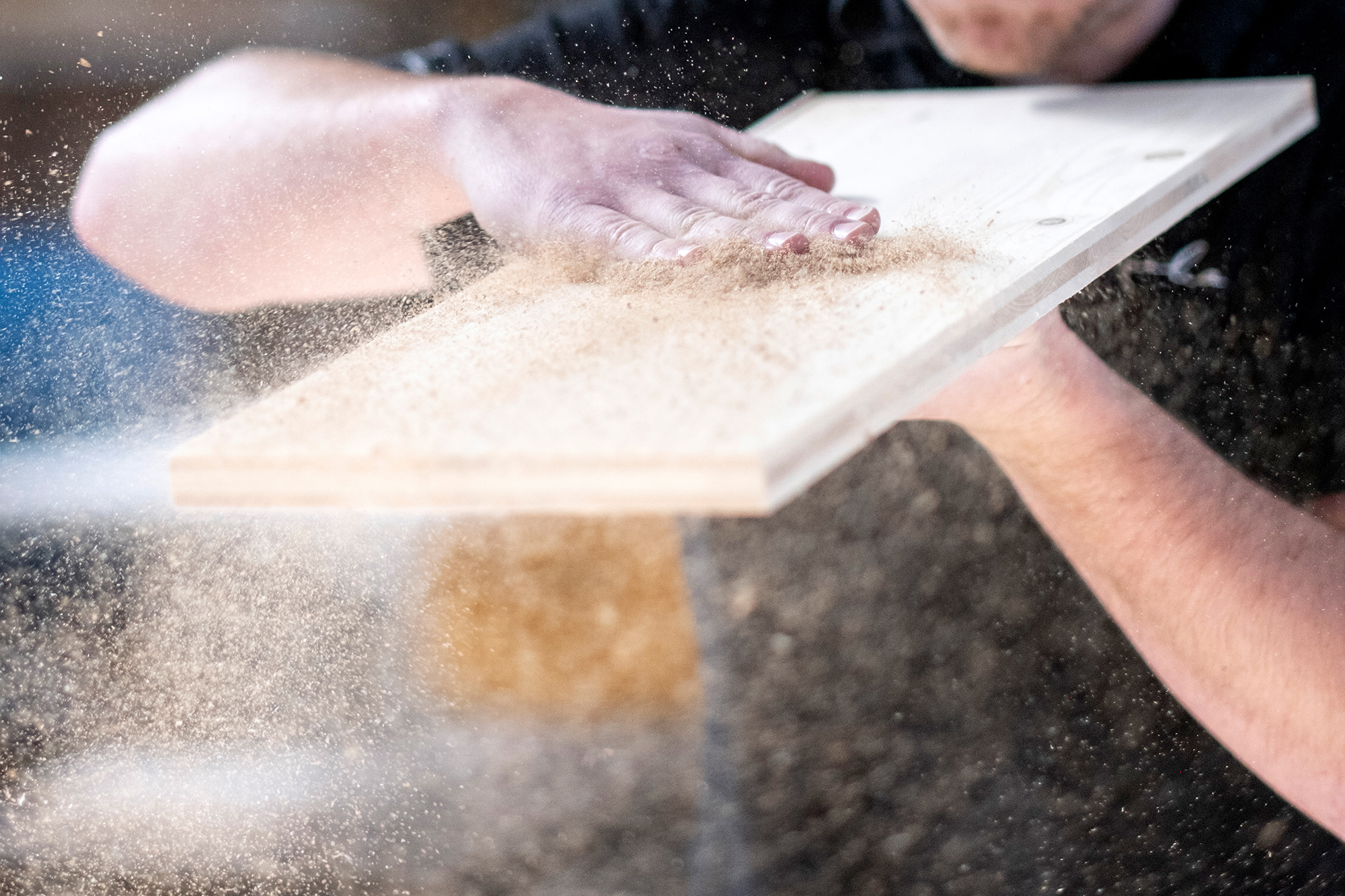 Feine Holzarbeit im Detail: Hände entfernen Sägemehl von Holzoberfläche im Innenausbau