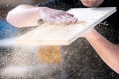 La raffinata lavorazione del legno nei dettagli: le mani rimuovono la segatura dalla superficie del legno durante la finitura degli interni