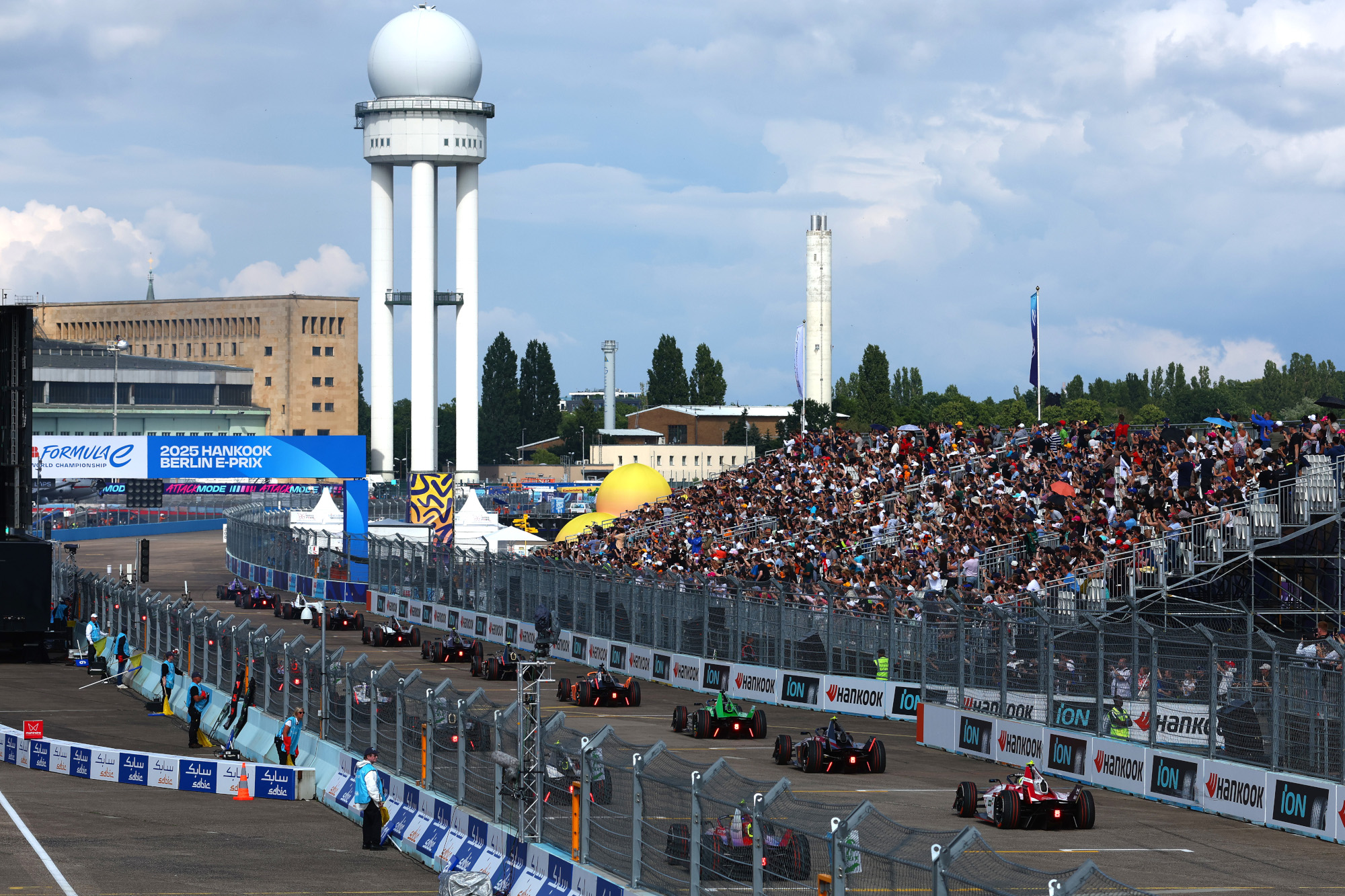 Vollbesetzte NÜSSLI-Tribüne beim 2025 Hankook Berlin E-Prix mit Formel-E-Fahrzeugen auf der Startgeraden