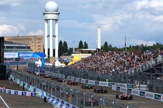 Tribuna NUSSLI llena en el Hankook Berlin E-Prix 2025 con monoplazas de Formula E en la recta