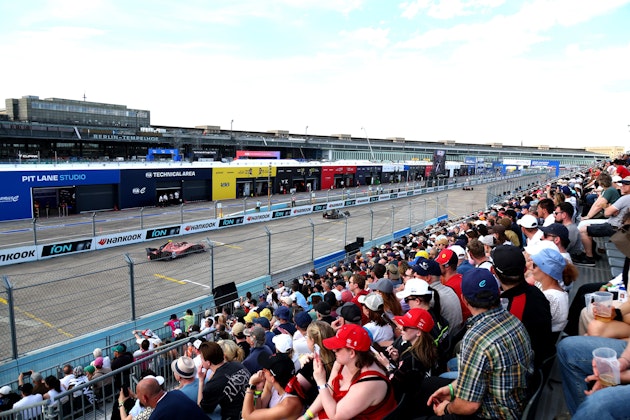 Tribuna NUSSLI repleta de espectadores junto a la recta de boxes en el E-Prix de Berlín, aeropuerto de Tempelhof al fondo.