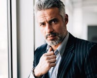 Handsome man with gray hair next to window.