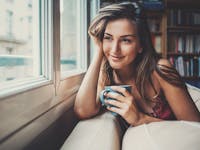 woman sitting by window drinking coffee