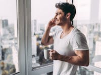 Handsome man on the phone smiling and looking out a window,