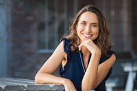 Woman with beautiful eyebrows sitting at table smiling.