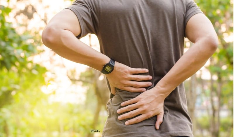 Man holding his back, signifying back pain.