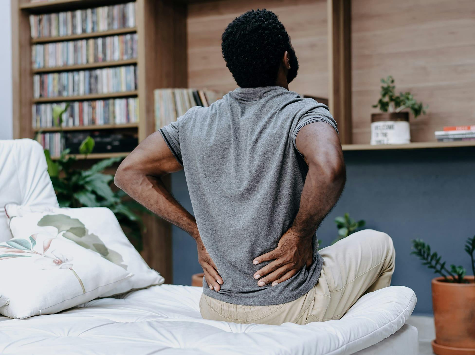 man sitting on a couch, holding his lower back