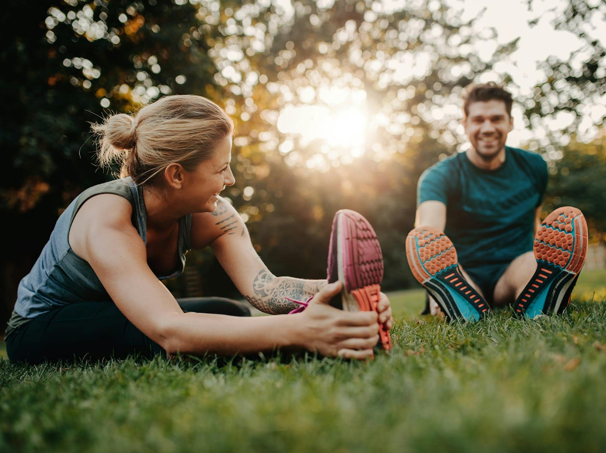 man and woman sitting in grass, stretching