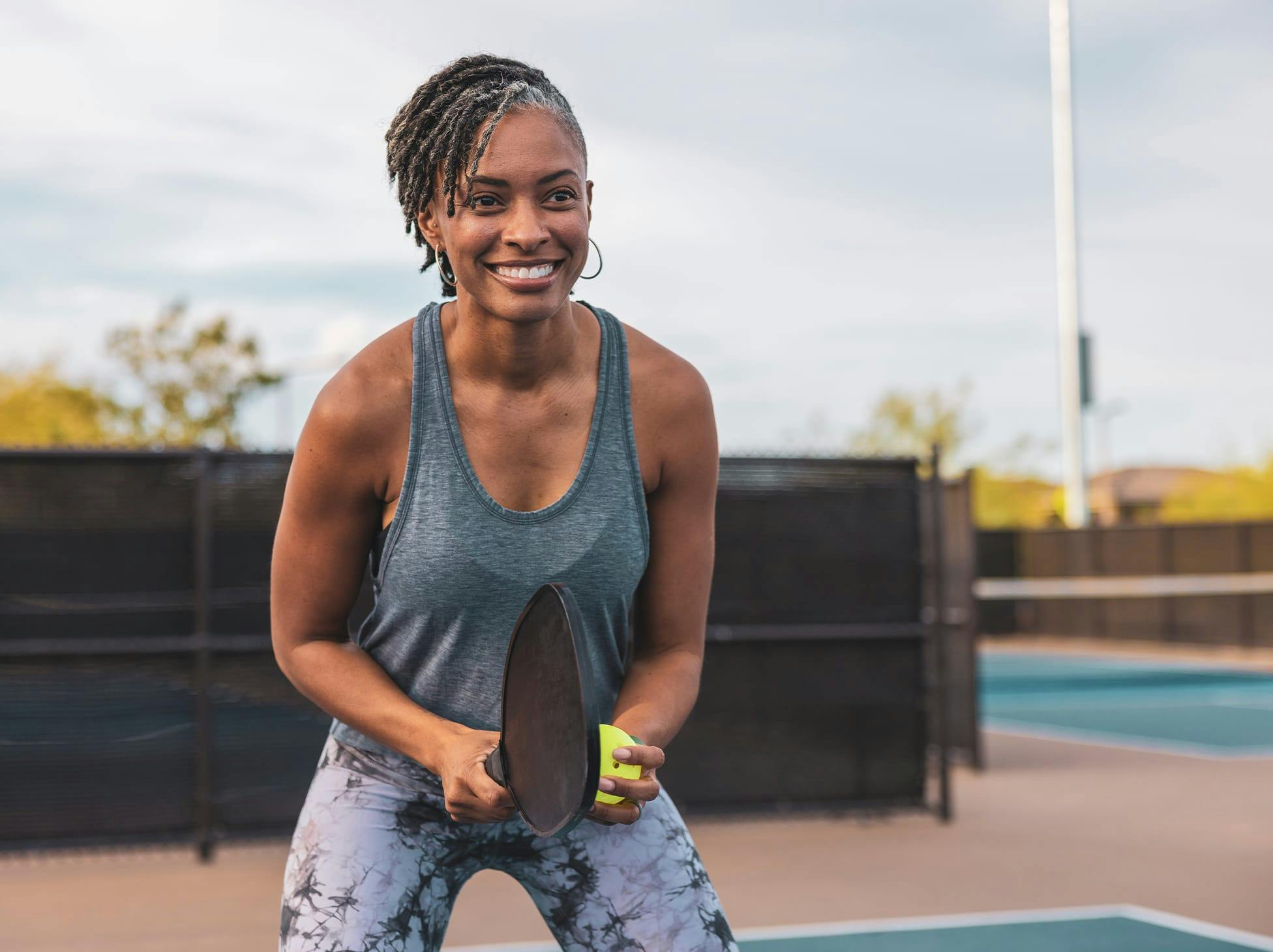 older woman holding a pickle ball and racket