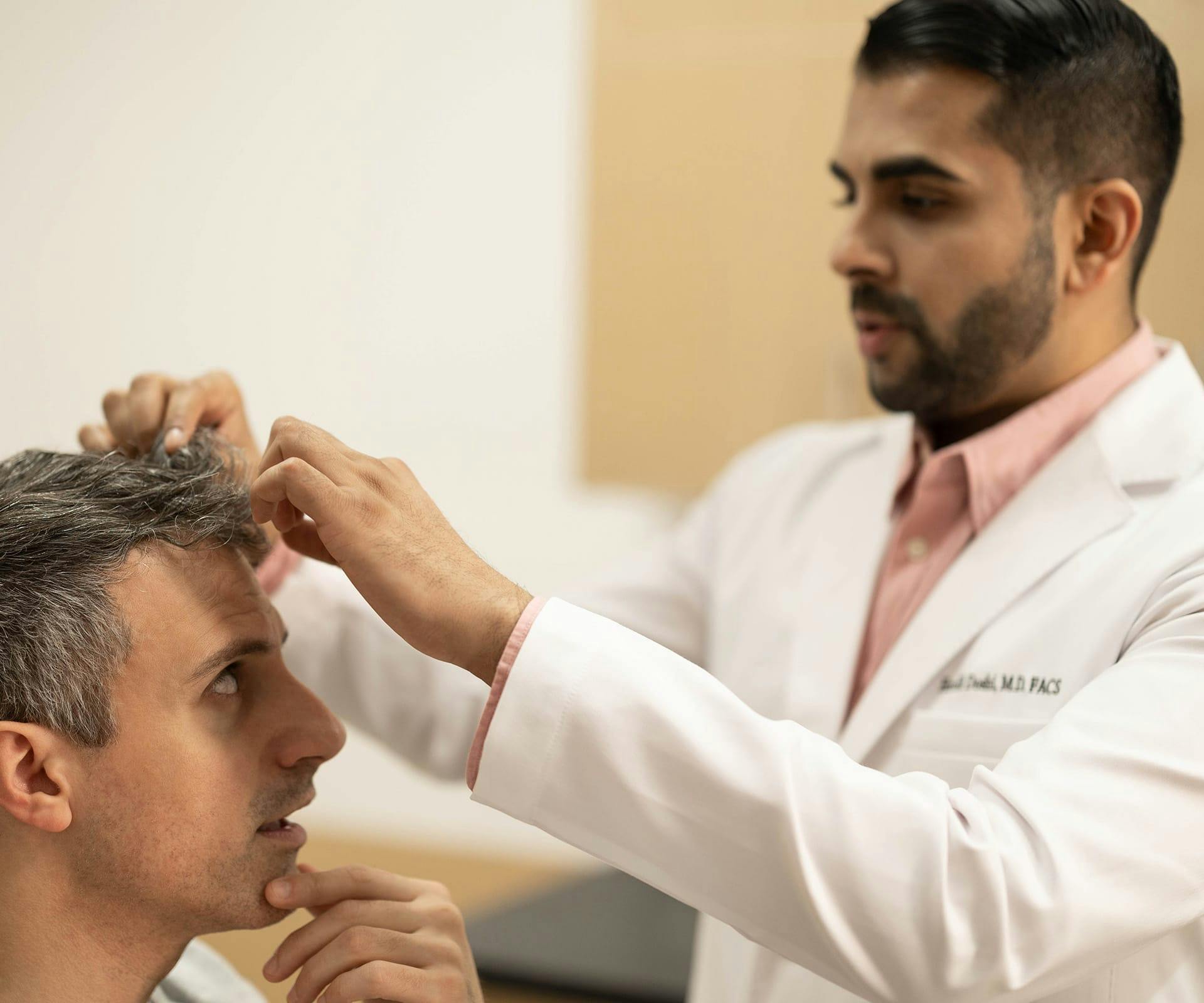 man getting his hair and scalp looked at by doctor