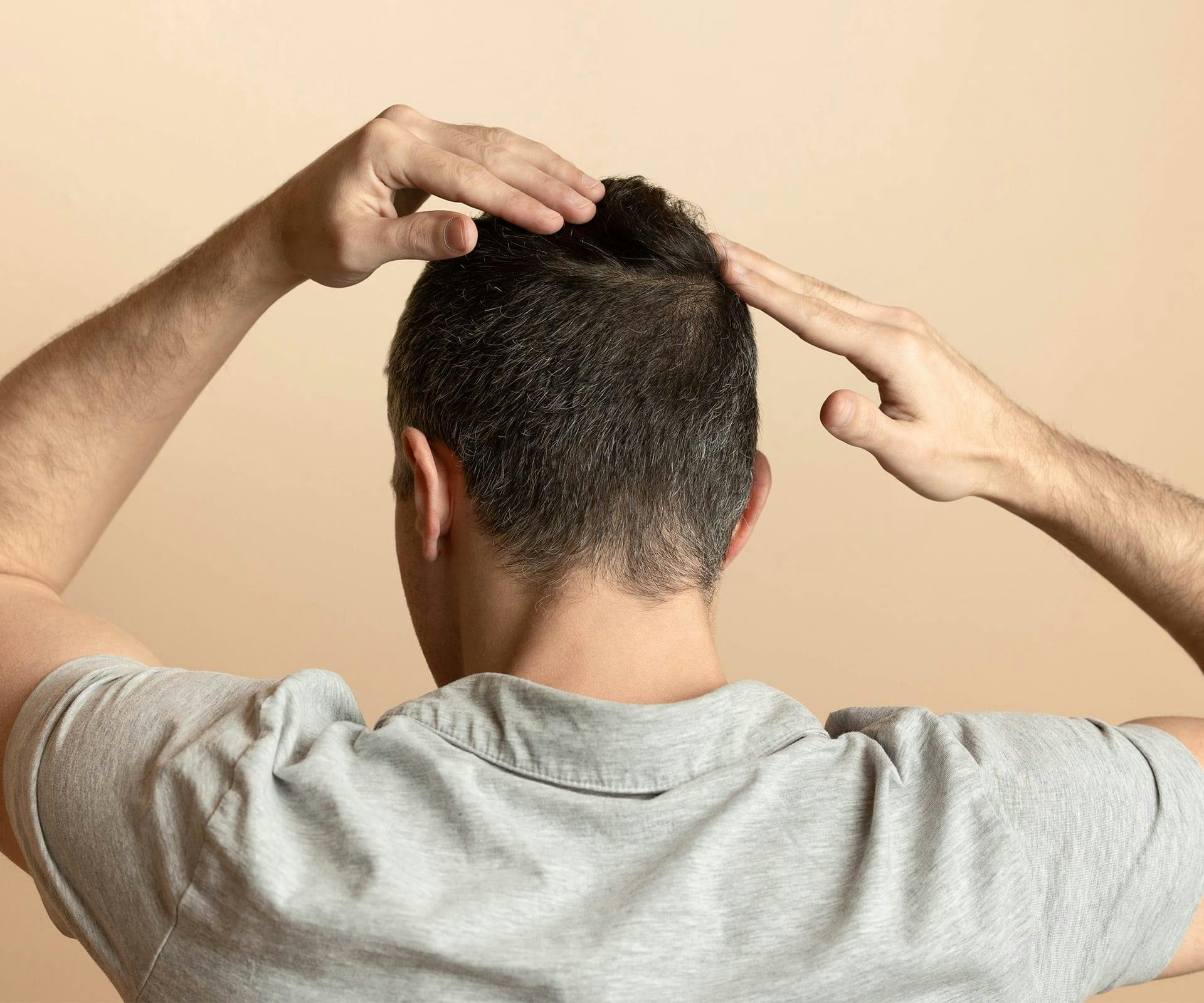 man facing backwards touching his hair