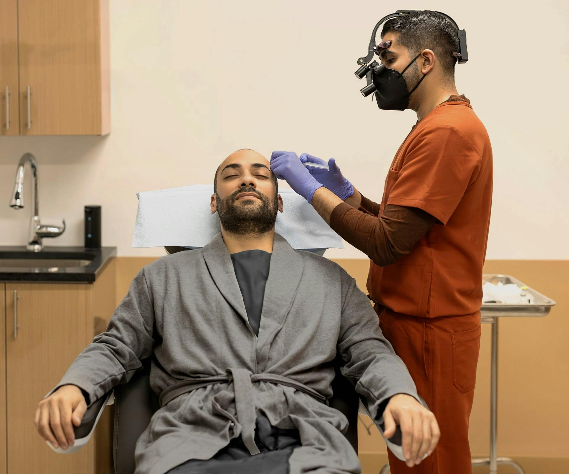 doctor looking at mans scalp as hes in exam chair leaning back