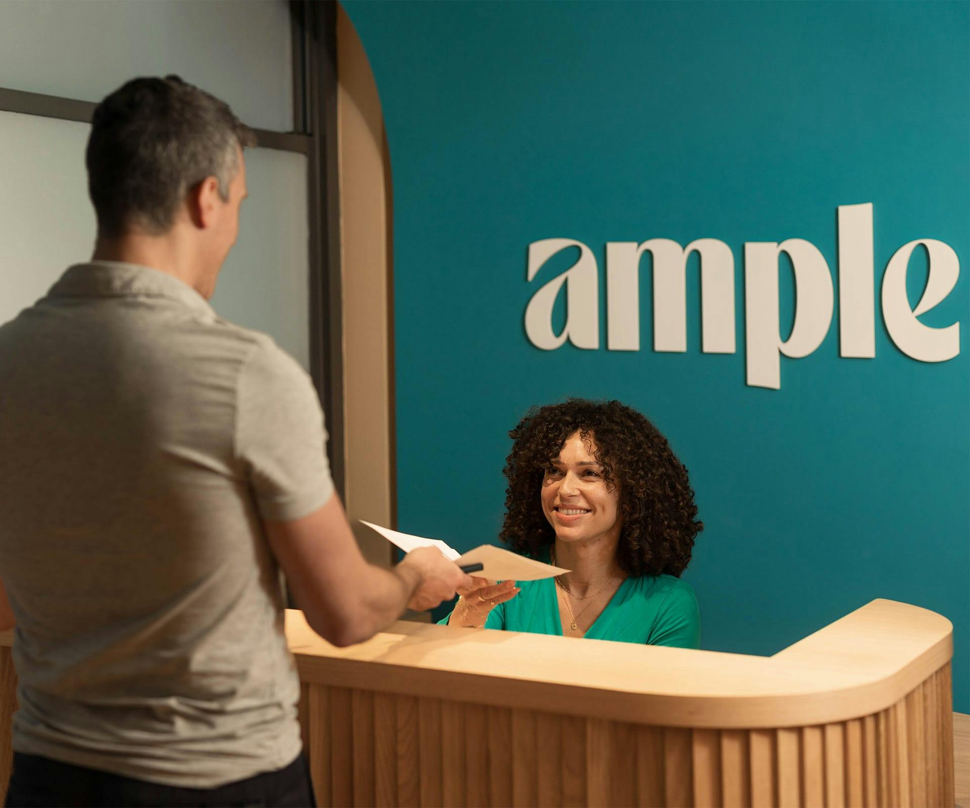 man giving form to receptionist at front desk