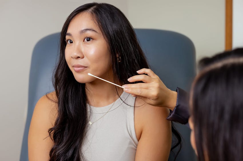 woman sitting in examination chair with another woman looking at her chin