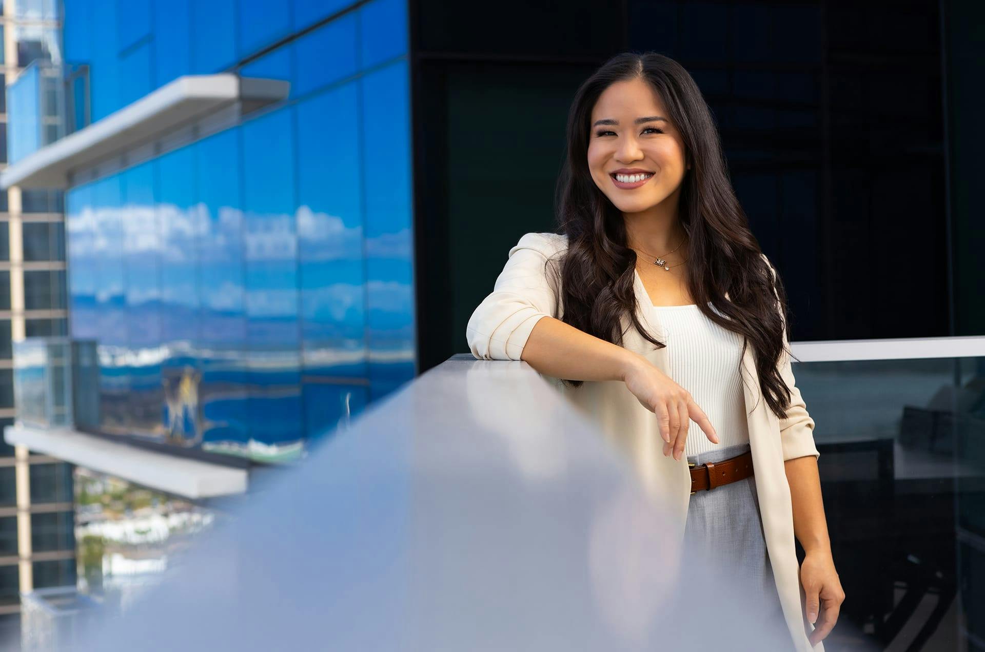 woman smiling and leaning on railing of rooftop