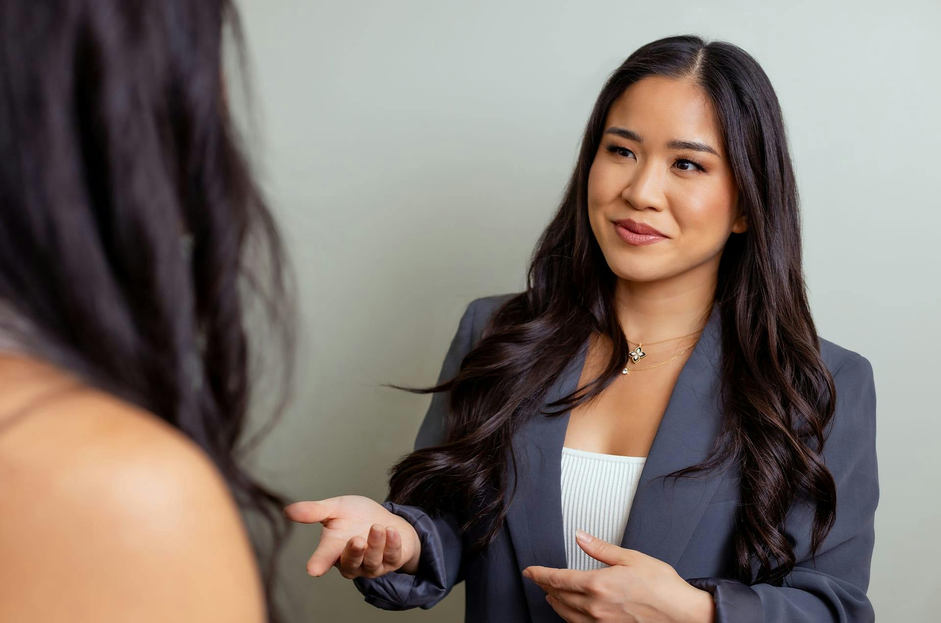 woman in suit jacket speaking to another woman