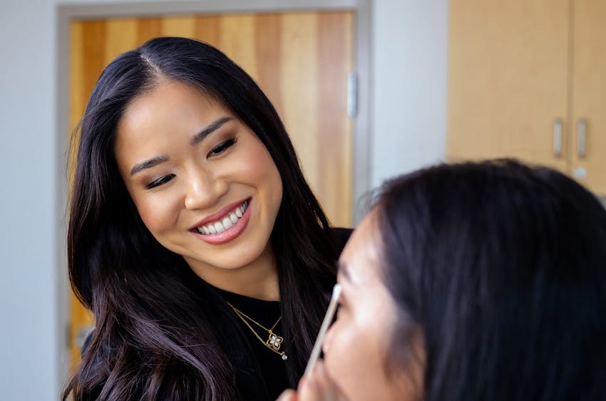 woman smiling while examining another woman's eyes