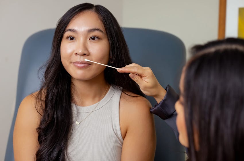 woman in examination chair with another woman examining her lips