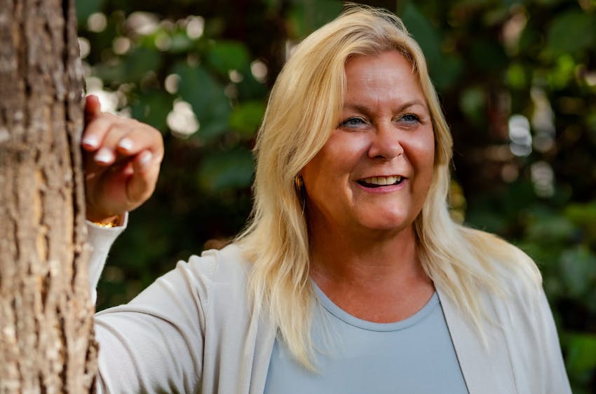woman smiling with her hand on a tree