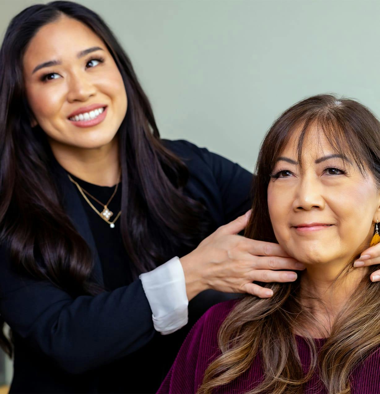 woman smiling while examining another woman's neck