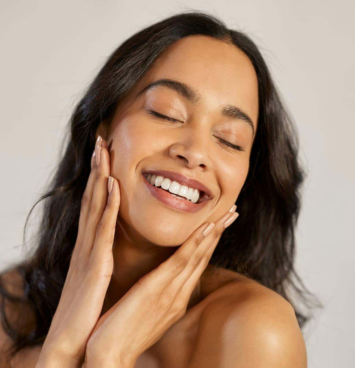 woman smiling with her eyes closed with her hands on her cheeks