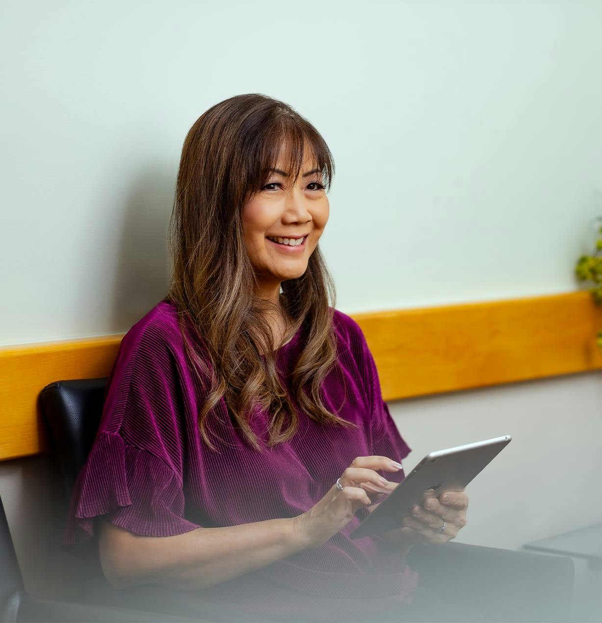 woman smiling while sitting down on ipad