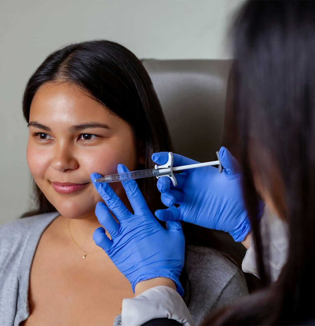 woman in examination chair getting injection in her lip