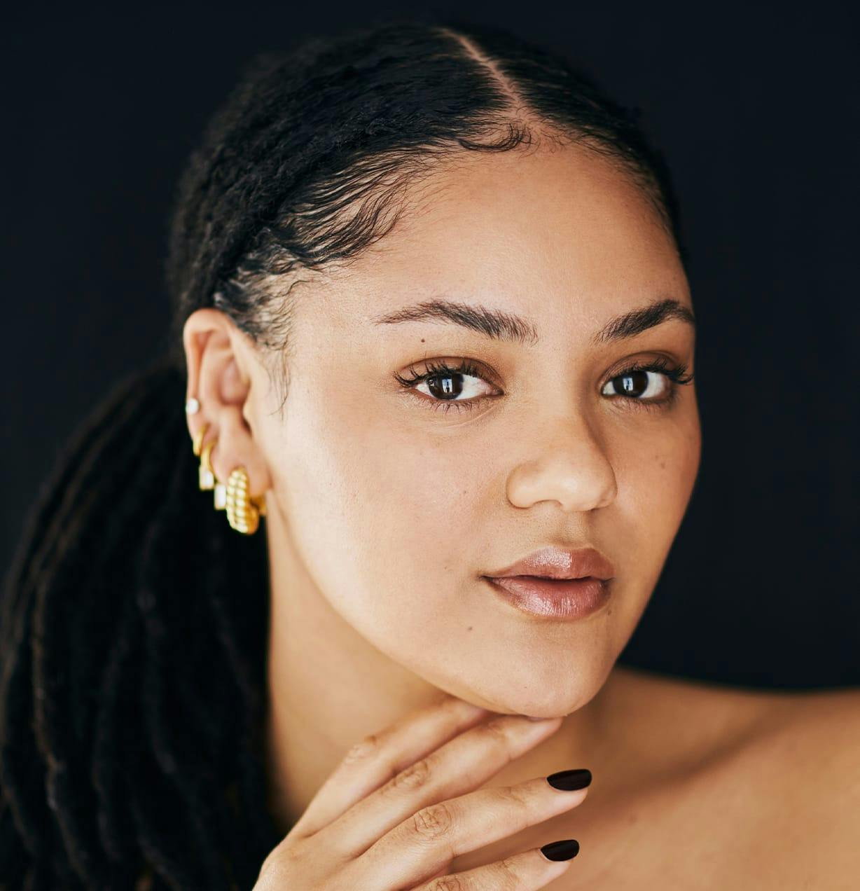 woman with ponytail with her fingers under her chin