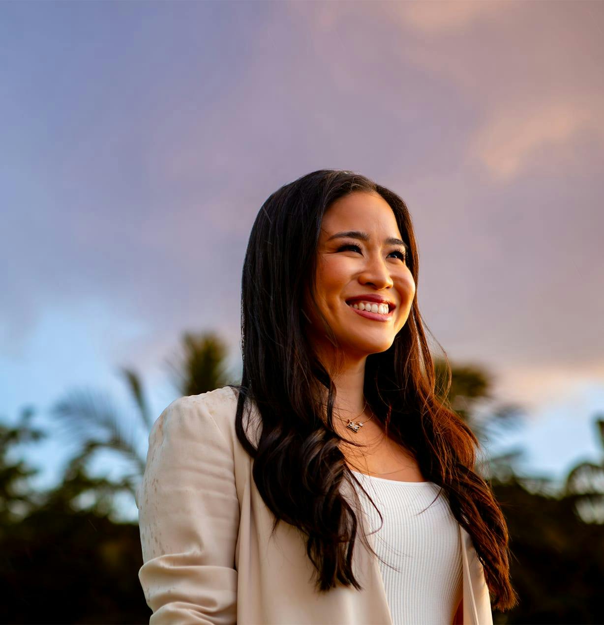woman smiling with sky and clouds behind her