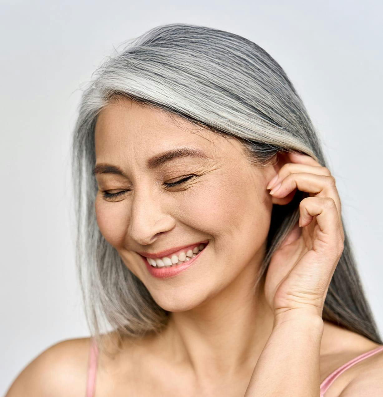 woman with gray hair moving her hair behind her ear