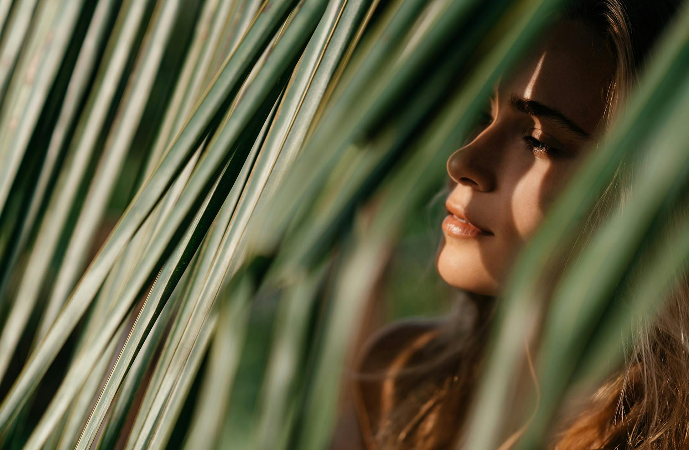 Woman looking through palm leaves