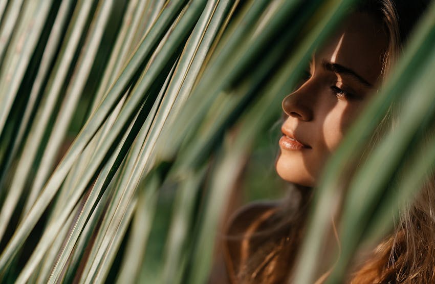 woman looking through the leaves of a plant