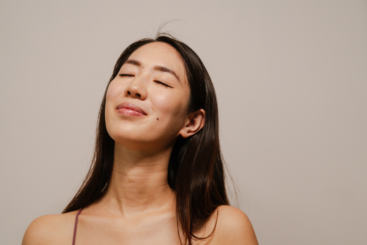 Asian woman with eyes closed smiling softly.