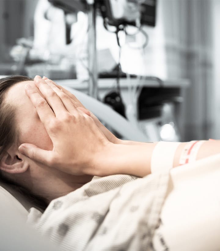person in a hospital bed, covering their face