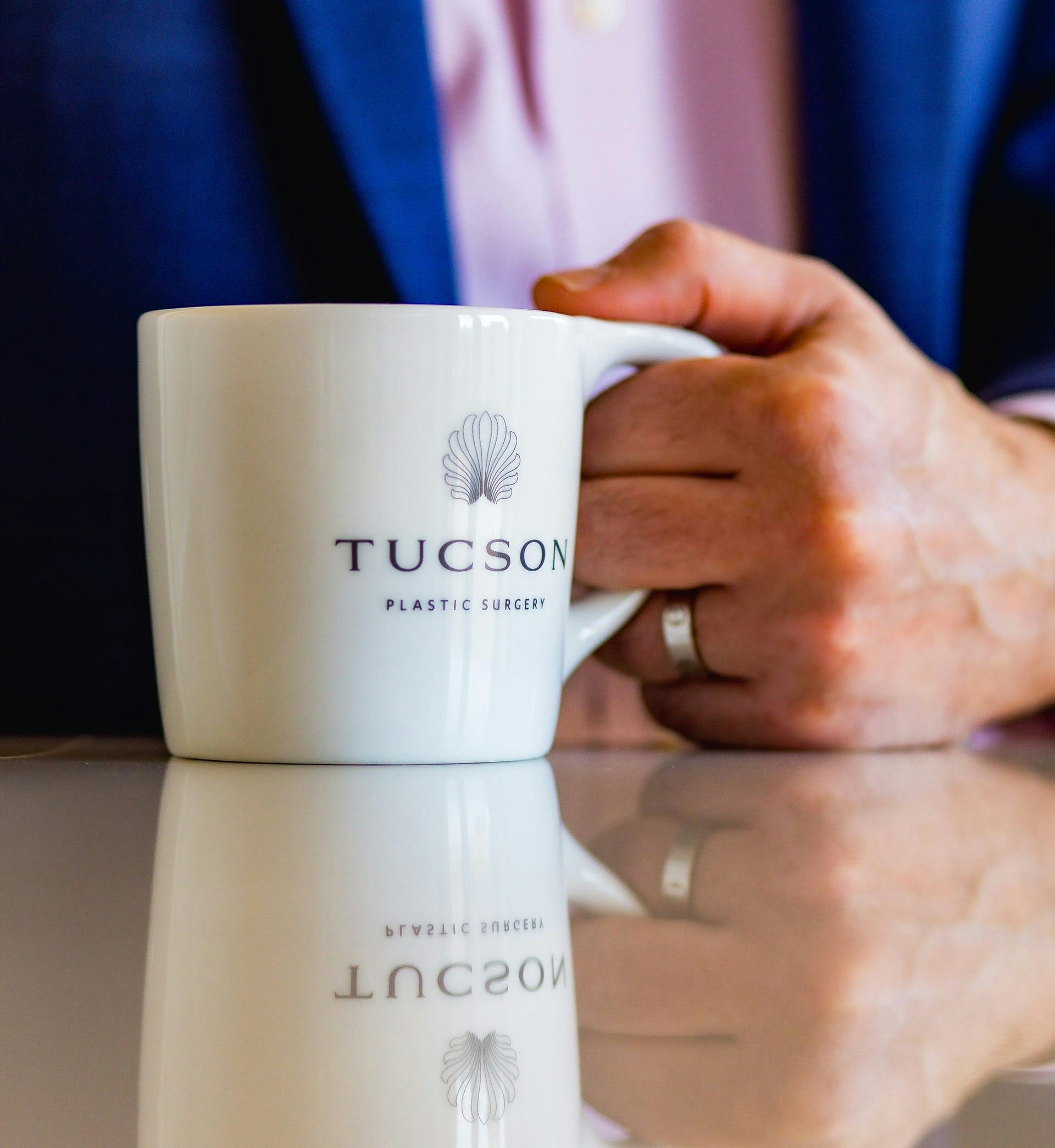 doctor holding a mug with the Tucson Plast Surgery logo